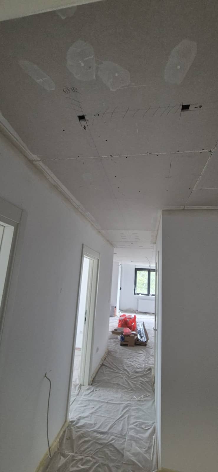 Hodnik u novogradnji pre radova: goli gipsani plafon sa obeleženim mestima za šinu